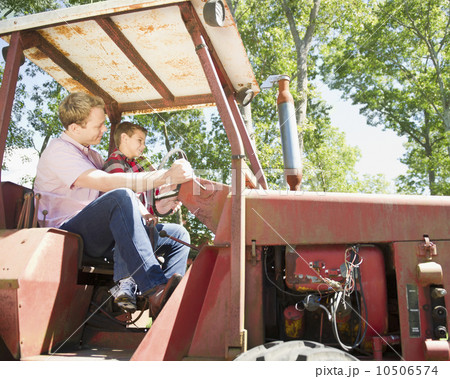 USA, New York, Flanders, Boy (8-9) with father sitting on tractor 10506574
