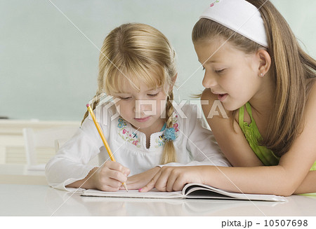 写真素材: Girl helping classmate at desk