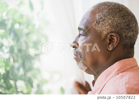 Portrait of man looking through window 10507822