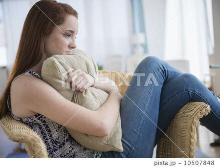 Teenage girl (14-15) sitting sad in armchair Teenage girl (14-15) sitting sad in armchair 10507848
