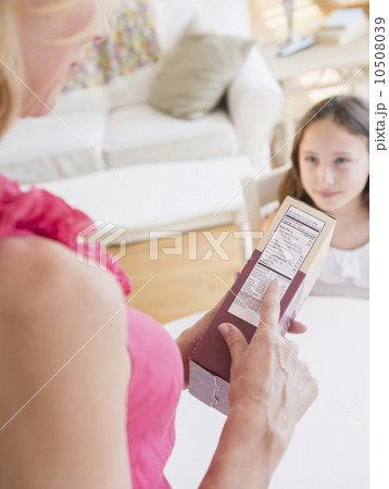 Mother reading nutrition label, daughter (8-9 years) in background 10508039
