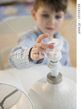 Boy (4-5) touching energy efficient lightbulb 10508198