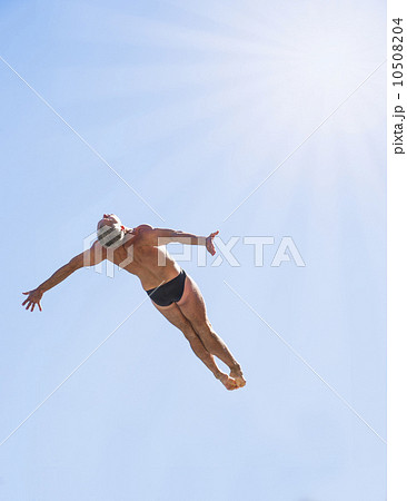 Athletic swimmer mid-air against blue sky Athletic swimmer mid-air against blue sky 10508204