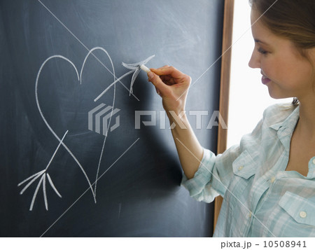 Woman writing heart on blackboard 10508941
