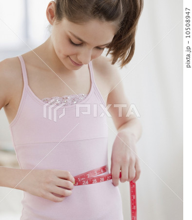 Preteen girl (10-12 years) measuring waist 10508947