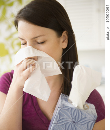 Young woman sneezing into tissue Young woman sneezing into tissue 10509092