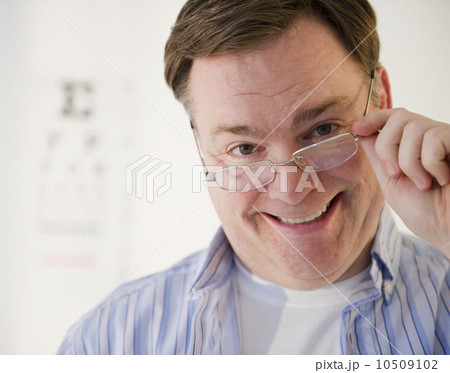 USA, Jersey City, New Jersey, portrait of man lowering glasses 10509102