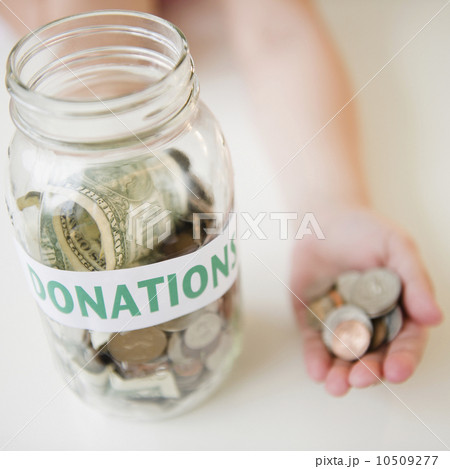 Close up of jar and girl's (10-11) hand holding coins 10509277