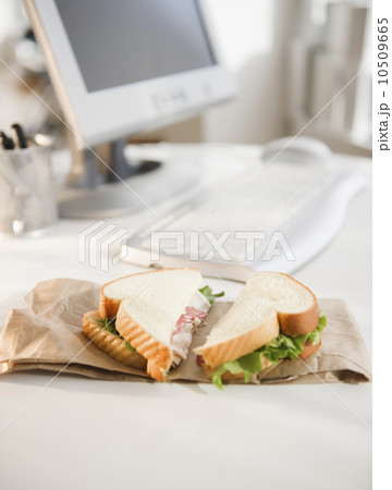 Sandwich on brown bag beside computer 10509665