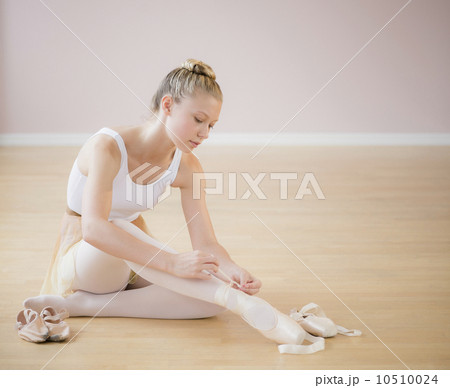 Portrait of teenage (16-17) ballet dancer tying her ballet shoe 10510024