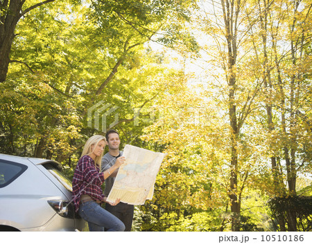 Couple leaning against car and reading map Couple leaning against car and reading map 10510186