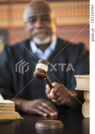 Judge holding gavel in courtroom 10510494