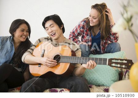 Young women listening to man playing guitar 10510930