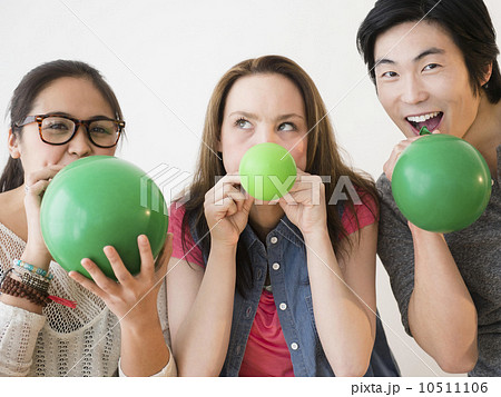 Portrait of young women and man blowing green balloons Portrait of young women and man blowing green balloons 10511106