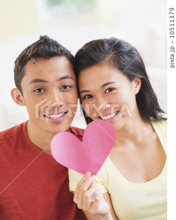 Portrait of young couple holding paper heart Portrait of young couple holding paper heart 10511379