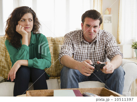 Couple sitting on sofa, man playing video game 10511397
