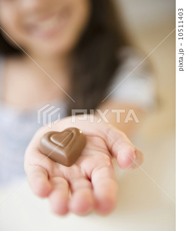 Close up of girl's (10-11) hand holding chocolate heart 10511403