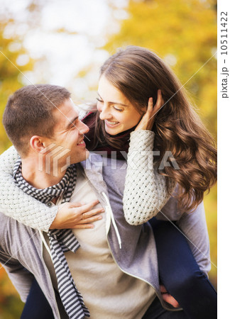 Man giving piggy back ride to woman in park Man giving piggy back ride to woman in park 10511422