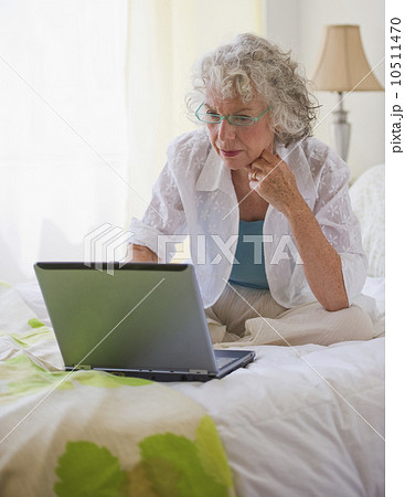 Woman looking at laptop in bedroom Woman looking at laptop in bedroom 10511470