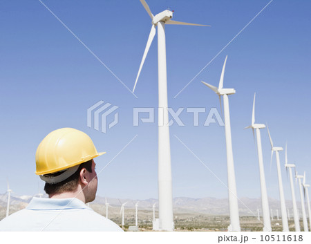 USA, California, Palm Springs, Coachella Valley, San Gorgonio Pass, Man in hard hat looking at wind turbines USA, California, Palm Springs, Coachella Valley, San Gorgonio Pass, Man in hard hat looking at wind turbines 10511618