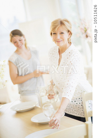 Mother and adult daughter setting table for dinner 10511626