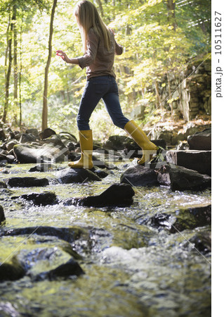 Woman walking on rocks in stream 10511627