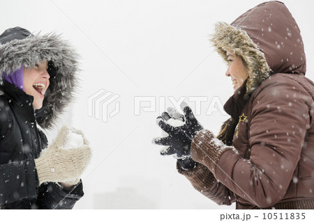 Two young women having snowball flight  10511835