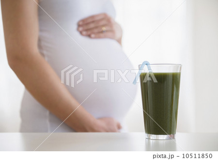 Mid section of pregnant woman, green smoothie in front Mid section of pregnant woman, green smoothie in front 10511850