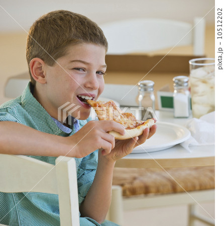 Boy (10-11) eating pizza 10512202