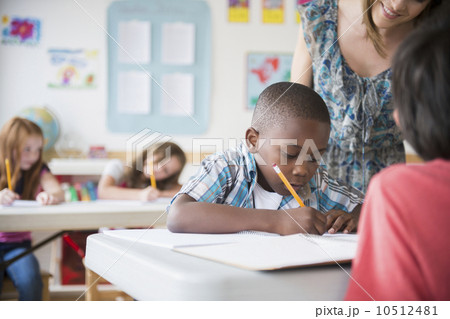 Children (8-9) with female teacher learning in classroom 10512481