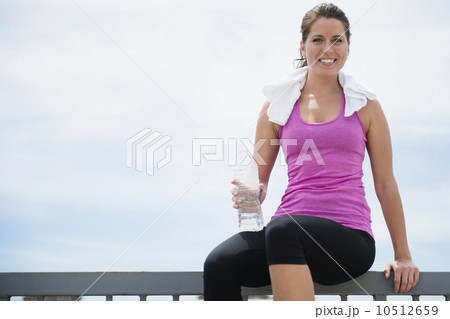 Woman taking break from exercising, sitting on railing 10512659