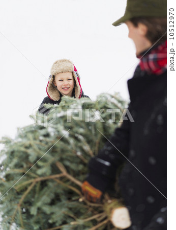 Father and son (6-7) carrying Christmas tree 10512970