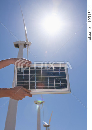 USA, California, Palm Springs, Woman's hands holding solar panel with wind turbines USA, California, Palm Springs, Woman's hands holding solar panel with wind turbines 10513114