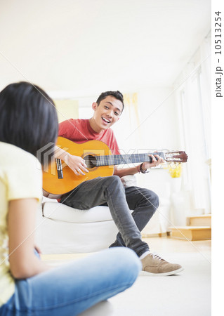 Young man playing guitar and singing, woman listening 10513254