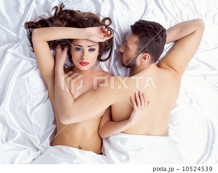 Image of weary young lovers lying on silk sheets 10524539