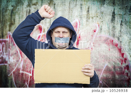 Demonstrator with a tape on a mouth and poster near to the wall Demonstrator with a tape on a mouth and poster near to the wall 10526938