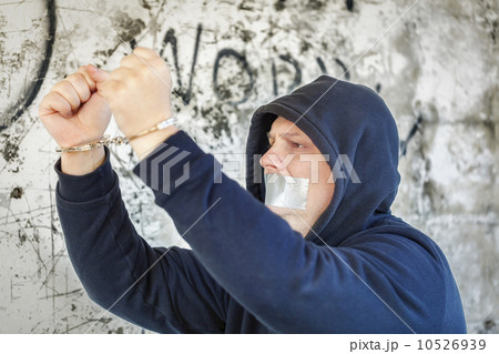 Hostage in handcuffs with tape on the mouth near wall Hostage in handcuffs with tape on the mouth near wall 10526939