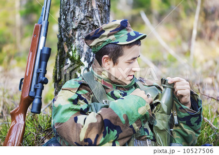 Young recruit with optical rifle in forest near tree 10527506
