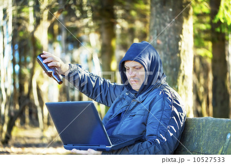 Man with beer bottle and PC in the park 10527533