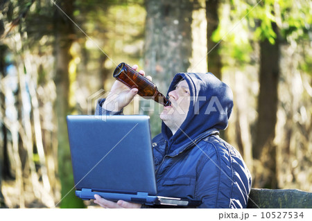 Man with beer bottle and PC in the park on a bench 10527534