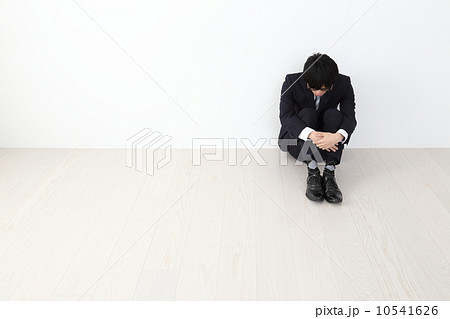 膝を抱えて座る男性社員の写真素材