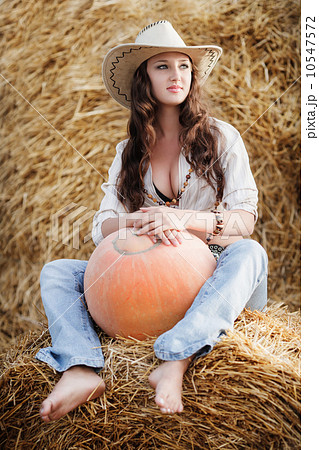 Pretty country cowgirl in hay with pumpkin 10547572