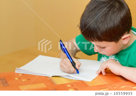 school boy writting homework in workbook 10559935