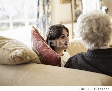 Two women, mother and daughter, sitting side by side, laughing. 10565778