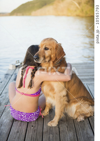 A young girl and a golden retriever dog sitting on a jetty. A young girl and a golden retriever dog sitting on a jetty. 10565793
