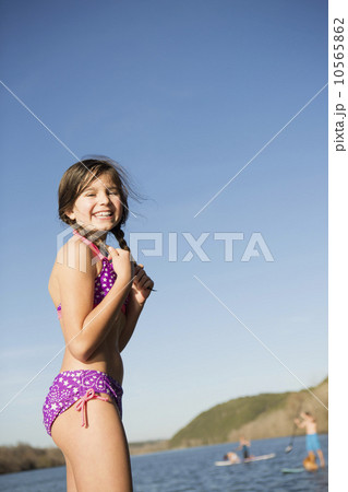 A young girl on a jetty with paddleboarders in the background. A young girl on a jetty with paddleboarders in the background. 10565862