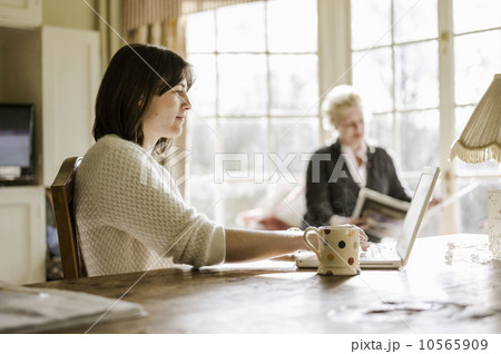 Two women at home seated at a kitchen table, mother and daughter 10565909