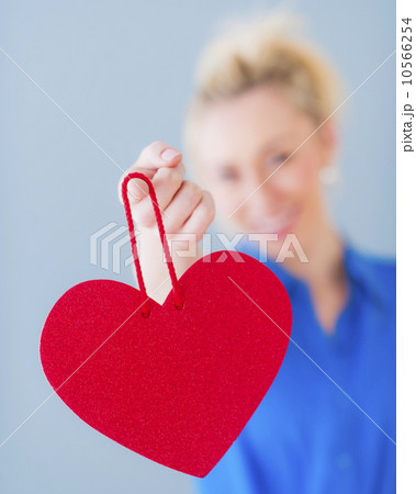 Close up of hand of young woman holding red heart, studio shot 10566254