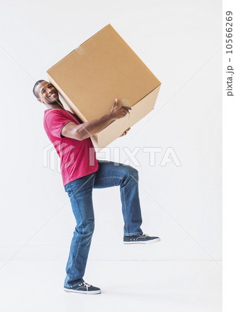 Studio shot of young man with large cardboard box Studio shot of young man with large cardboard box 10566269