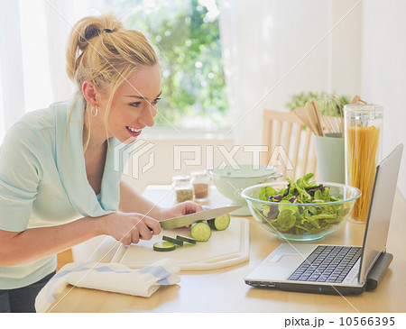 Smiling young woman using laptop in kitchen Smiling young woman using laptop in kitchen 10566395